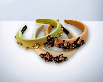 May include: Three satin headbands with jeweled butterfly embellishments. The headbands are in shades of green, peach, and cream.