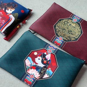 Könnte beinhalten: Drei dekorative Beutel mit asiatisch inspirierten Designs. Einer ist blau mit einer Frau im Kimono, ein anderer bordeauxfarben mit einem goldenen Drachen und der dritte ist türkis mit einer Katze in einem floralen Design. Jeder Beutel hat einen Reißverschluss.