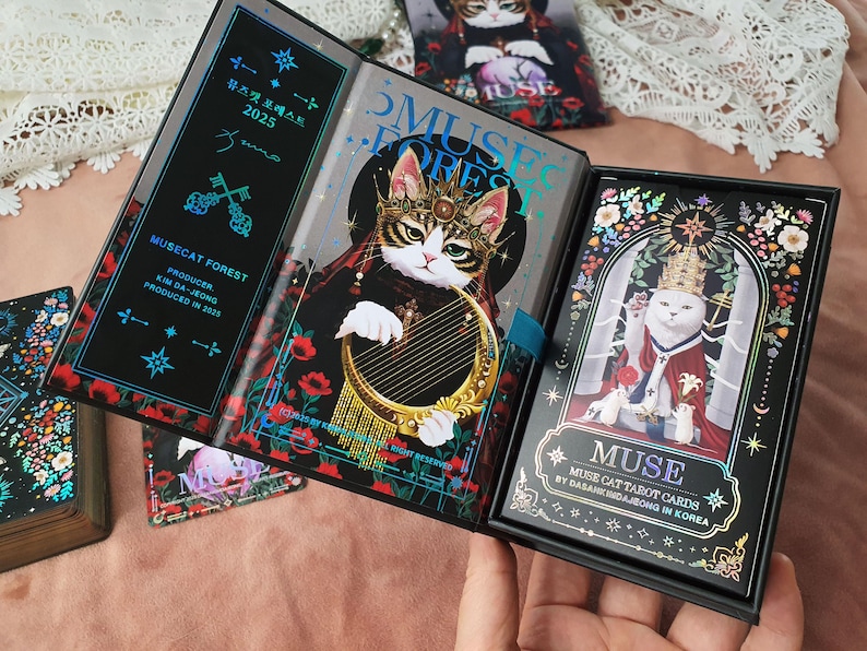 K&ouml;nnte beinhalten: Ein Tarotkartenset mit einer Katze mit Krone und Harfe, betitelt "Musecat Forest 2025". Die Box und das Buch haben Blumen- und Schl&uuml;sselmuster, mit dem Wort "MUSE". Das Set enth&auml;lt eine Box und ein Buch.