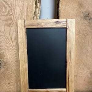 May include: A rustic wooden frame with a black chalkboard insert. The frame has a natural wood finish with visible grain and knots.