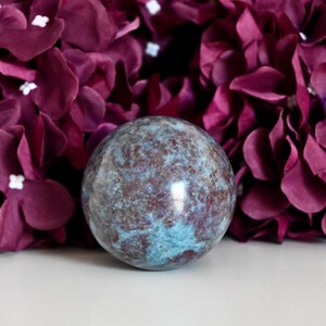 Peut inclure: Une sphère bleue et brune en kyanite, une variété de pierre précieuse. La sphère est lisse et polie, avec un motif tourbillonnant de bleu et de brun.