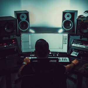 May include: A home music studio setup featuring a computer monitor, keyboard, and audio equipment. Two large speakers are positioned on either side of the monitor. The scene is dimly lit, creating a focused workspace.