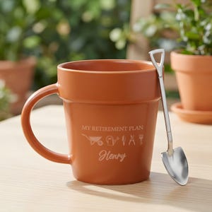 May include: A terracotta-colored ceramic mug shaped like a flower pot, featuring the text "MY RETIREMENT PLAN" above icons of a wheelbarrow, watering can, trowel, shears, and rake, with the name "Henry" below. A silver metal shovel-shaped spoon.
