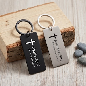 May include: Two rectangular keychains with a cross design. One is black with "Psalm 46:5" and "God is within her..." in white. The other is silver with "Jeremiah 29:11" and "For I know the plans..." in black.
