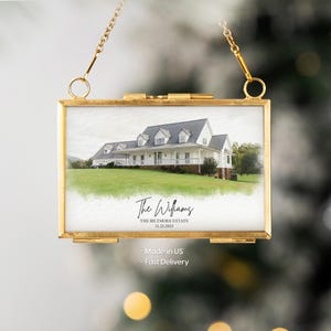 May include: A rectangular gold-toned metal picture frame with a chain for hanging. The frame holds a watercolor-style image of a white house with a green lawn. The text "The Williams" and "The Biltmore Estate 11.25.2025" are visible.