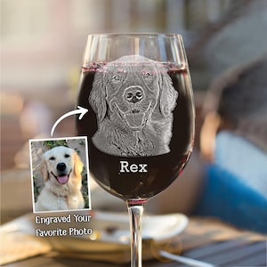 May include: A wine glass filled with red wine, featuring an engraved image of a dog's face. The dog's name, "Rex," is etched below the image. A smaller photo of the dog is displayed next to the glass, with the text "Engraved Your Favorite Photo."