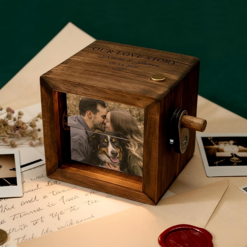 May include: A wooden photo cube with a rotating mechanism, displaying a couple kissing and a dog. The top of the cube is engraved with "OUR LOVE STORY" and a date. The cube is made of dark wood.