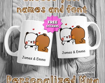 May include: Two white ceramic mugs with a cartoon panda and bear design, kissing. The mugs have the names "James & Emma" printed on them. The image includes the text "Choose your names and font", "FREE STICKERS", and "Personalized Mug".