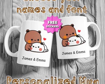 May include: Two white ceramic mugs with a cartoon bear and mochi design, personalized with the names "James & Emma." The mugs have a handle and a heart graphic. Text on the image reads "Choose your names and font," "Free Stickers," and "Personalized Mug."