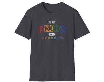 Op de afbeelding: Donkergrijs t-shirt met de tekst "IN MY PRIDE ERA" in regenboogkleuren. Onder de tekst staan zeven kleine regenbooghartjes. Het shirt heeft een ronde hals en korte mouwen.