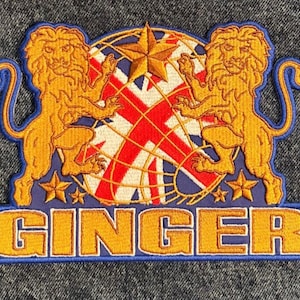 Peut inclure: Un écusson brodé or avec deux lions encadrant un globe avec un motif Union Jack et une étoile. Le texte "GINGER" est sous le globe.