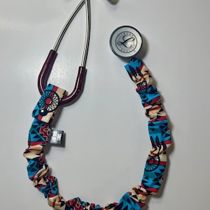 May include: A stethoscope with a patterned cover in shades of blue, red, and beige. The stethoscope has a maroon tube and silver earpieces. The cover has a geometric design and the text "LUB DUB LABS".