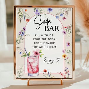 Puede incluir: Un letrero enmarcado con borde dorado, con las palabras "Soda BAR" e instrucciones para hacer soda. El letrero está decorado con flores de acuarela y una ilustración de bebida rosa. También se incluye el texto "Enjoy".