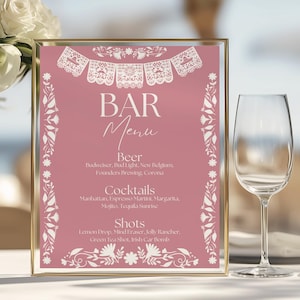May include: A rectangular bar menu sign with a dusty rose background and white decorative borders featuring papel picado-style banners and floral motifs. The text reads: BAR Menu, Beer, Budweiser, Bud Light, New Belgium, Founders Brewing, Corona, Cocktails, Manhattan, Espresso Martini, Margarita, Mojito, Tequila Sunrise, Shots, Lemon Drop, Mind Eraser, Jolly Rancher, Green Tea Shot, Irish Car Bomb.