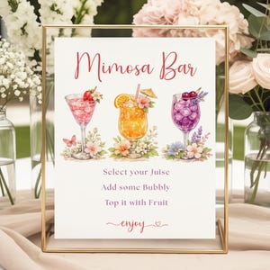 Może przedstawiać: Prostokątny znak w złotej ramie z napisem Mimosa Bar, Select your Juise, Add some Bubbly, Top it with Fruit oraz enjoy. Znak zawiera akwarelowe ilustracje trzech koktajli ozdobionych owocami i kwiatami.