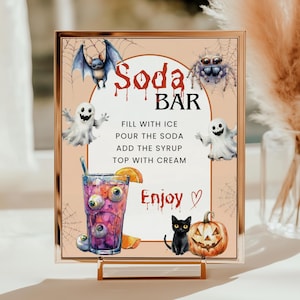 May include: A Halloween-themed sign with a gold frame, featuring a "Soda Bar" design. The sign includes illustrations of a bat, spider, ghost, black cat, and jack-o'-lantern. A purple drink with eyeballs is shown. The text reads "Fill with ice, pour the soda, add the syrup, top with cream."