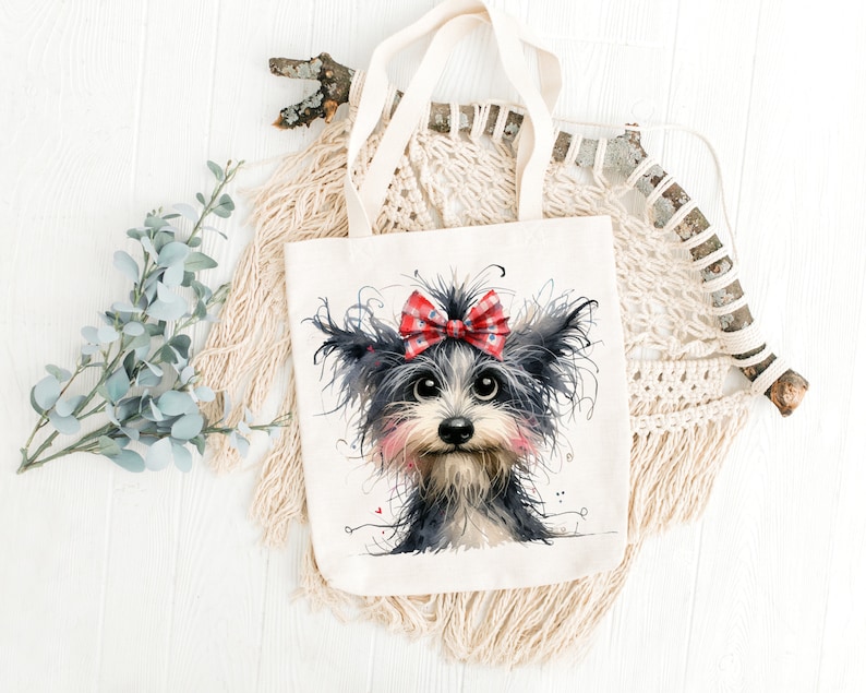 May include: A white tote bag with a black and white illustration of a dog wearing a red and white bow. The dog has a pink nose and black eyes.