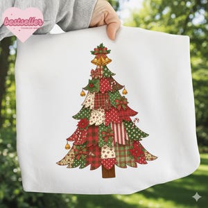 Puede incluir: Bolso tote blanco con un diseño de árbol de Navidad colorido. El árbol está compuesto por varios parches estampados en rojo, verde y beige, adornado con lazos, campanas y un bastón de caramelo. La palabra "bestseller" está en un corazón rosa.
