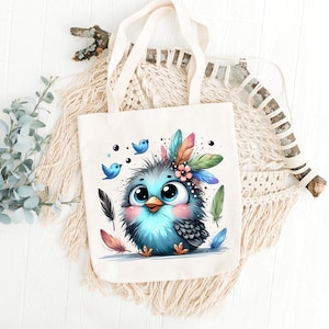 Puede incluir: Una bolsa de tela blanca con un p&aacute;jaro azul que lleva un tocado de plumas de colores. El p&aacute;jaro tiene ojos grandes y un rubor rosado. Dos p&aacute;jaros azules m&aacute;s peque&ntilde;os vuelan detr&aacute;s del p&aacute;jaro principal.