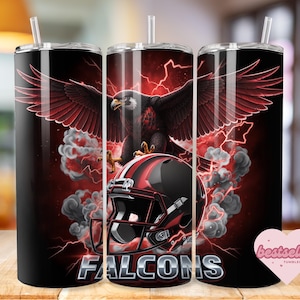 May include: A black tumbler with a red and black design featuring a soaring eagle, a football helmet, and the word "Falcons." The design includes red lightning bolts and smoke effects. The tumbler has a straw and a lid.