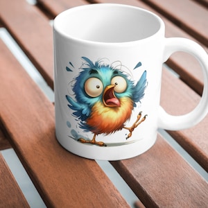 Puede incluir: Taza de cer&aacute;mica blanca con una ilustraci&oacute;n de dibujos animados de un p&aacute;jaro azul y naranja con ojos grandes y el pico abierto. El p&aacute;jaro est&aacute; representado en una pose asustada con las alas extendidas.