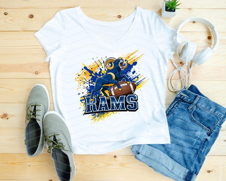 May include: White v-neck t-shirt featuring a blue and gold graphic of a ram with a football and the word "RAMS". The shirt is paired with denim shorts, gray sneakers, and white headphones.