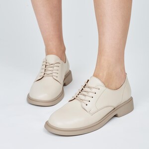 May include: A pair of cream-colored leather lace-up shoes with a chunky sole.