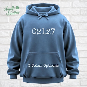 May include: A blue hoodie with a front pocket and drawstring hood. The number "02127" is printed in white on the front. The text "3 Color Options" is below the number. The hoodie has the "South Southie" logo in the upper left corner.