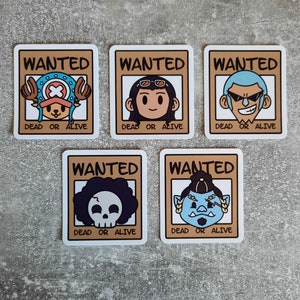 May include: Five wanted posters with cartoon characters. Each poster has a brown background with the word "WANTED" in white letters at the top. The text "DEAD OR ALIVE" is at the bottom of each poster. The characters are a pirate with a straw hat, a woman with sunglasses, a man with a shaved head, a skull with a black afro, and a blue troll with a single eye.