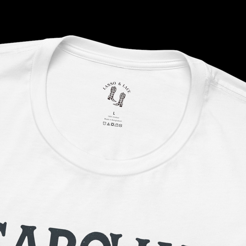 May include: White t-shirt with a black graphic print of the text "CAROLYN" and a small black and white label with the text "LASSO & LACE" and a pair of cowboy boots.