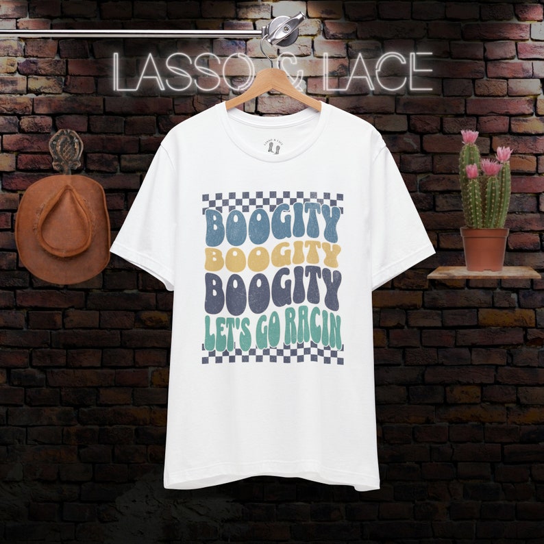 May include: White t-shirt with a checkered background and the text "Boogitty Boogitty Boogitty Let's Go Rac'n" in a retro font.