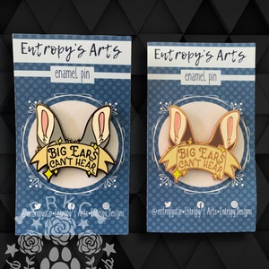Puede incluir: Dos pines de esmalte con un perro de dibujos animados con orejas grandes y el texto "BIG EARS CAN'T HEAR". Los pines están en cartulina azul y blanca con el texto "Entropy's Arts" y "enamel pin".