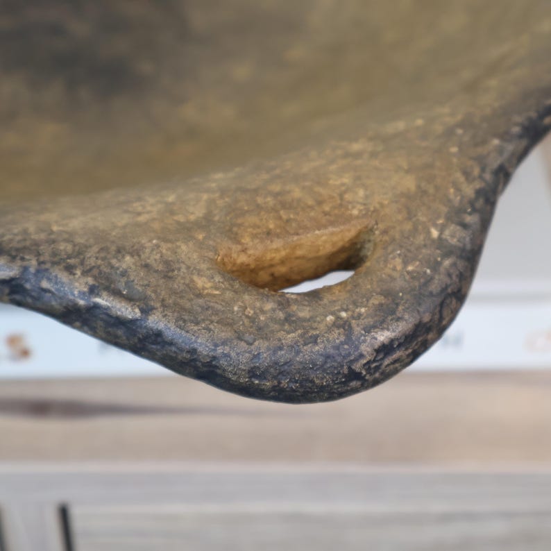 May include: Close-up of a textured, brown and black ceramic bowl with a handle. The bowl has a rustic appearance with a natural, earthy color palette. The handle features a circular opening.