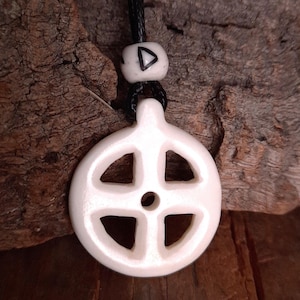 May include: White ceramic pendant with a wheel design, hanging from a black cord with a white bead featuring a triangle symbol.