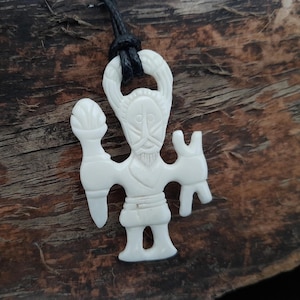 May include: White bone pendant carved in the shape of a human figure with a beard and holding a staff. The pendant is on a black cord.