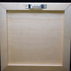 May include: The back of a light wood picture frame with a metal hanging hook attached to the top.
