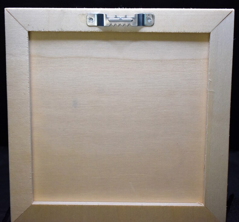 May include: The back of a light wood picture frame with a metal hanging hook attached to the top.