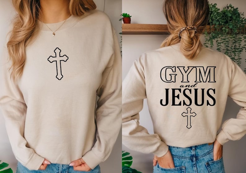May include: A beige sweatshirt with the text "GYM and JESUS" and a cross on the back. The front of the sweatshirt has a cross.