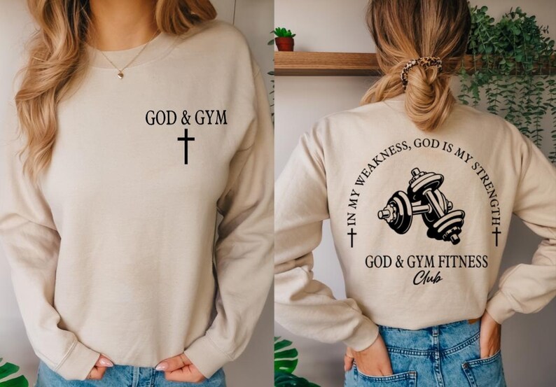 May include: A beige sweatshirt with the text "GOD & GYM" and a cross on the front. The back of the sweatshirt has the text "IN MY WEAKNESS, GOD IS MY STRENGTH" with a cross on each side and a dumbbell graphic in the center. The text "GOD & GYM FITNESS Club" is below the graphic.