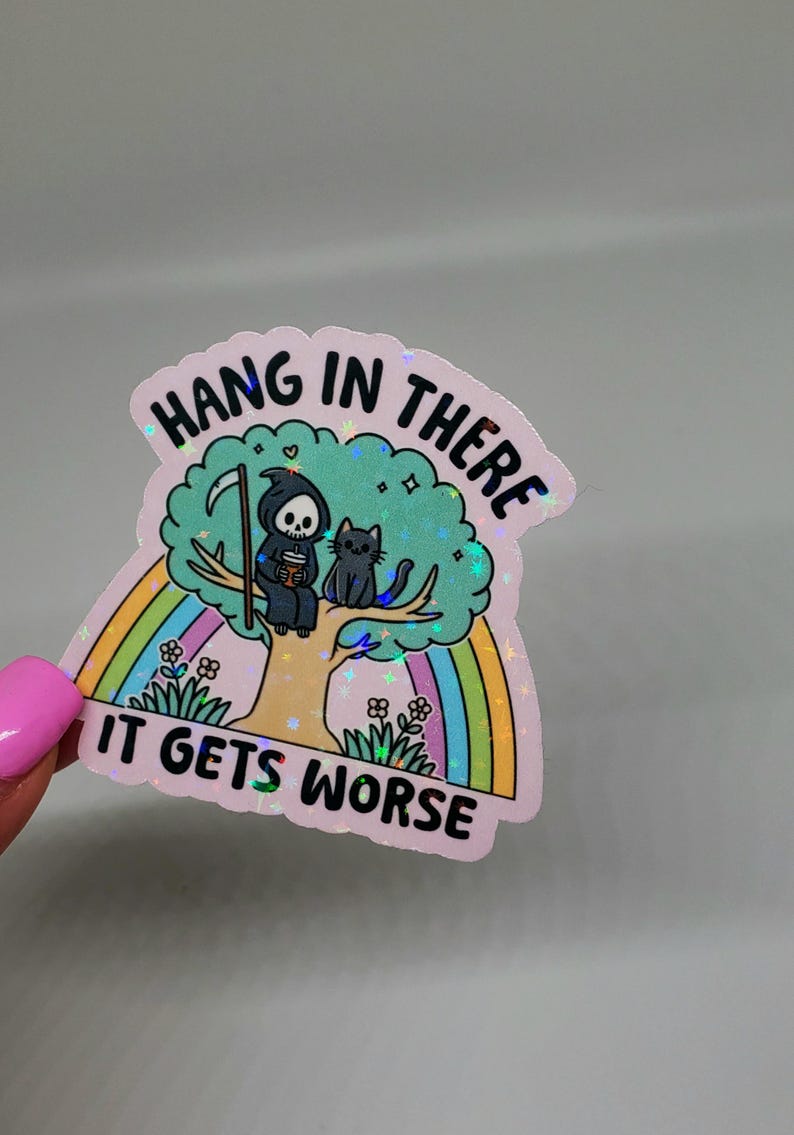 Op de afbeelding: Een roze holografische sticker met een cartoon afbeelding van de Grim Reaper die op een boom zit met een kat. De sticker heeft een regenboog en de tekst "Hang in there it gets worse".