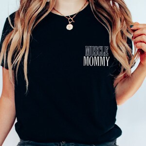 May include: Black t-shirt with the text "MUSCLE MOMMY" printed in white on the front.