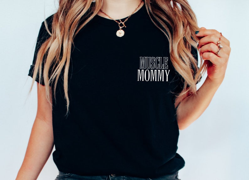 May include: Black t-shirt with the text "MUSCLE MOMMY" printed in white on the front.