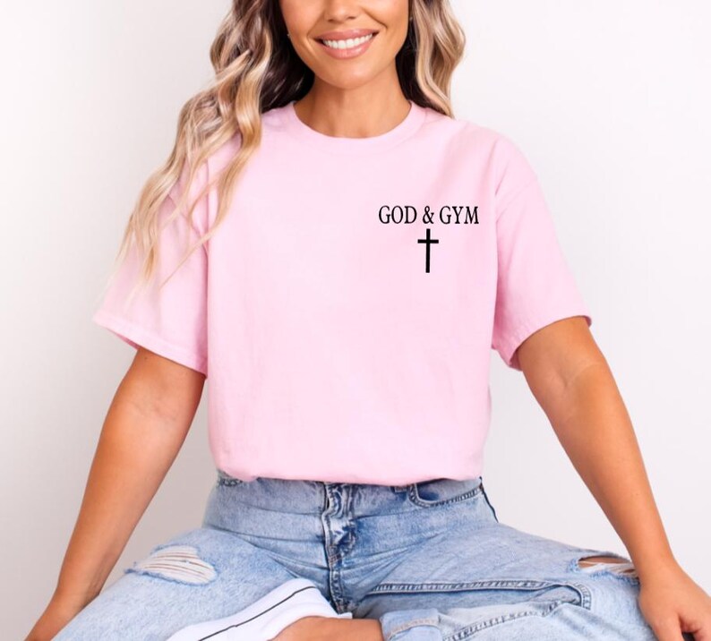 May include: A pink t-shirt with the text "GOD & GYM" and a cross printed on the front.