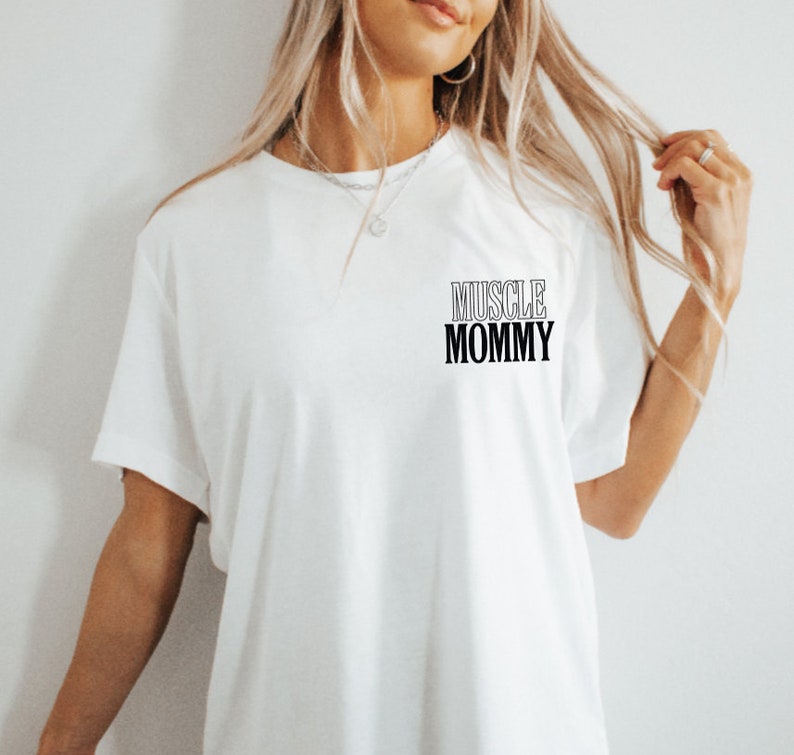 May include: White t-shirt with black text that reads "MUSCLE MOMMY" on the front.