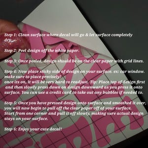 May include: A pink decal being applied to a surface. The image shows the steps for applying the decal, including cleaning the surface, peeling the design, and smoothing it onto the surface. The text in the image provides instructions.