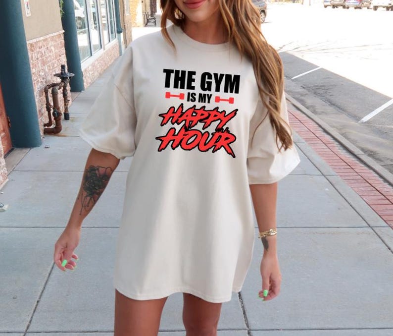 Peut inclure: Un t-shirt blanc surdimensionn&eacute; avec un motif rouge et noir qui dit "The Gym is my Happy Hour".