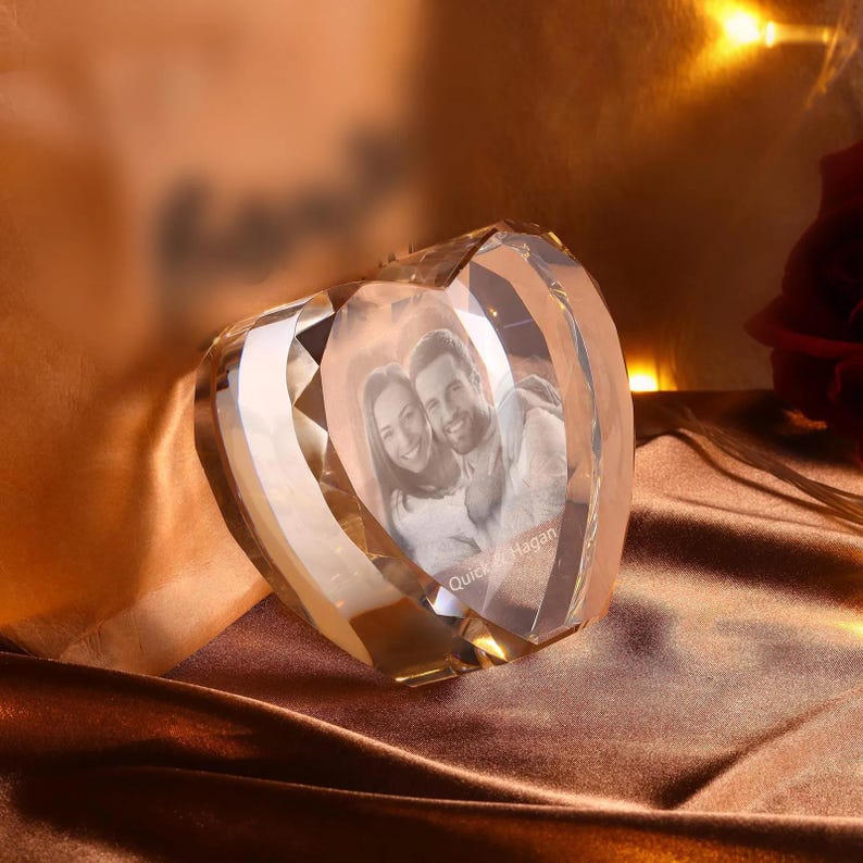 May include: A crystal heart-shaped paperweight with a 3D engraved image of a couple inside. The couple is smiling and the text "Quick & Hagan" is engraved below them.