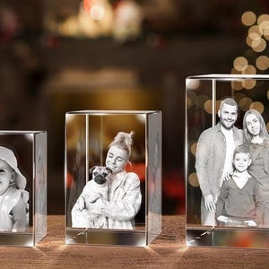 May include: Three crystal cubes with engraved images. The first cube shows a young child wearing a hat. The second cube shows a woman holding a small dog. The third cube shows a family of three.