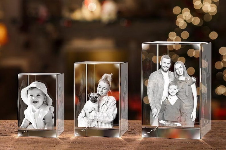 May include: Three crystal cubes with engraved images. The first cube shows a young child wearing a hat. The second cube shows a woman holding a small dog. The third cube shows a family of three.