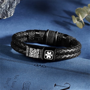 May include: Black leather bracelet with a stainless steel clasp and a medical alert tag. The tag has a star of life symbol and the words "HEALTH INFO" and "SCAN ME".